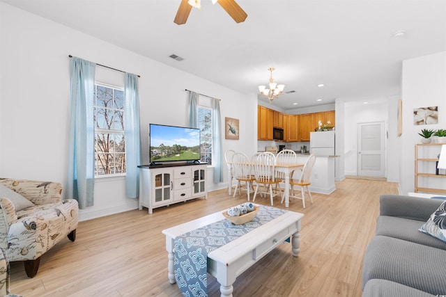 living room with plenty of natural light, ceiling fan with notable chandelier, and light hardwood / wood-style floors