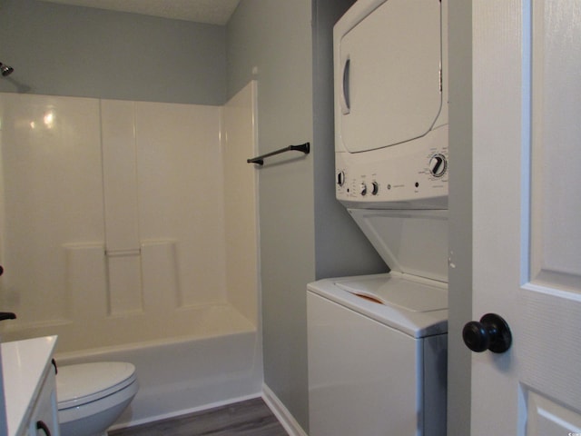 full bathroom with hardwood / wood-style flooring,  shower combination, stacked washer and clothes dryer, vanity, and toilet