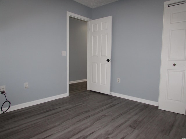 unfurnished room with dark wood-type flooring and a textured ceiling