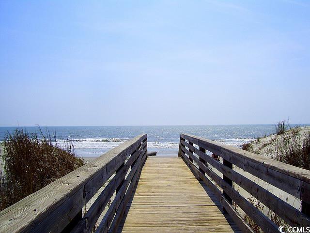 view of dock featuring a water view and a beach view