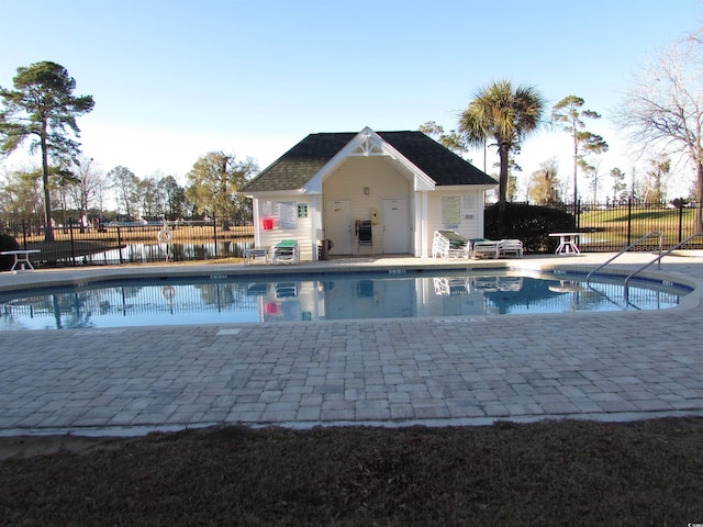 view of swimming pool featuring an outbuilding and a patio