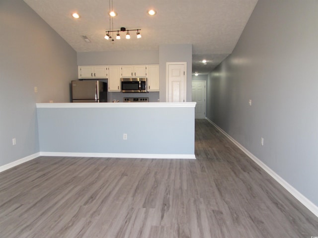 kitchen featuring stainless steel appliances, white cabinetry, dark wood-type flooring, and pendant lighting