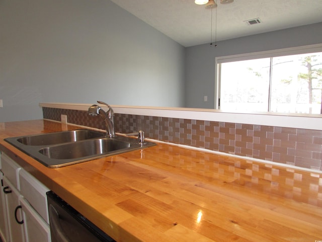 kitchen with butcher block counters, sink, backsplash, and black dishwasher