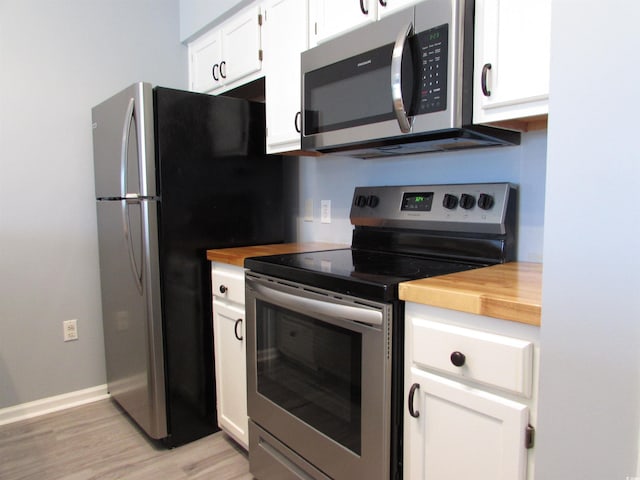 kitchen featuring stainless steel appliances, white cabinets, butcher block countertops, and light hardwood / wood-style flooring