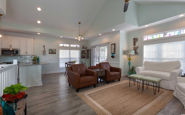 living room featuring high vaulted ceiling, sink, hardwood / wood-style flooring, and ceiling fan with notable chandelier