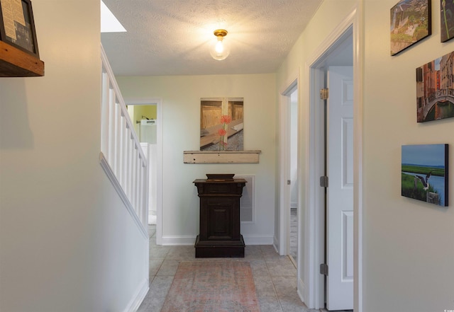 hallway with a textured ceiling and light tile patterned flooring