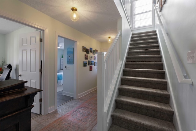 stairway featuring a textured ceiling and tile patterned floors