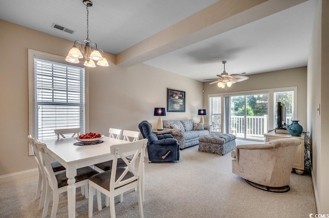 dining space featuring beamed ceiling, ceiling fan with notable chandelier, and light carpet