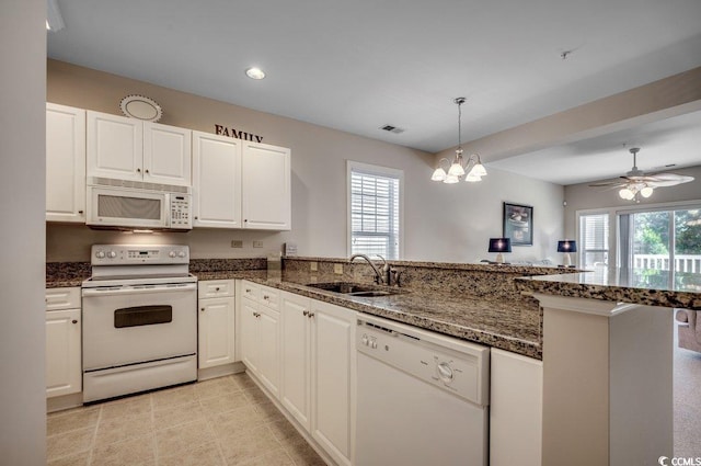 kitchen with white cabinetry, sink, dark stone countertops, kitchen peninsula, and white appliances