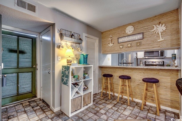 bar featuring a textured ceiling, appliances with stainless steel finishes, and sink