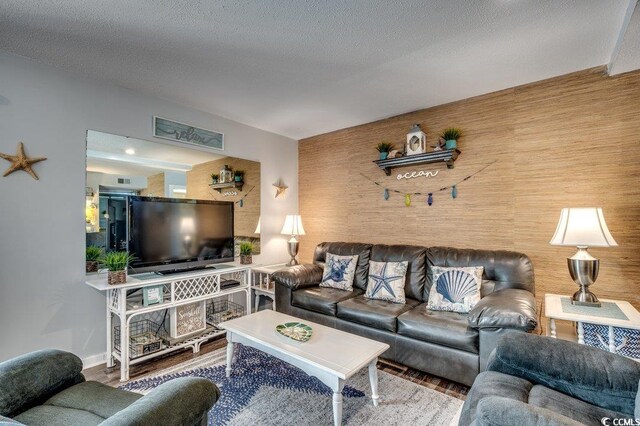 living room with a textured ceiling, hardwood / wood-style flooring, and wooden walls