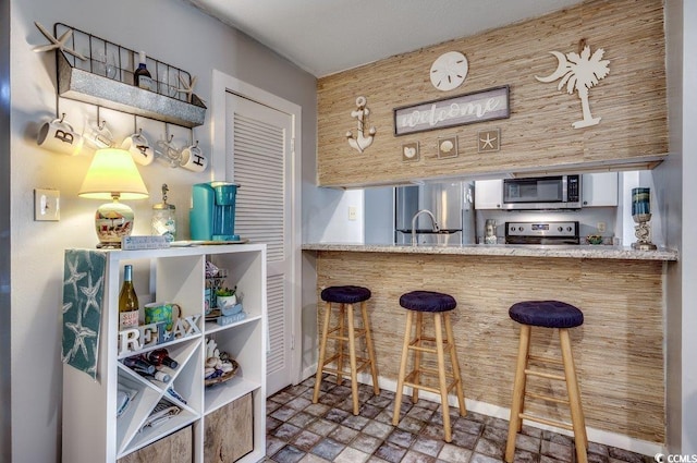 bar with sink and appliances with stainless steel finishes