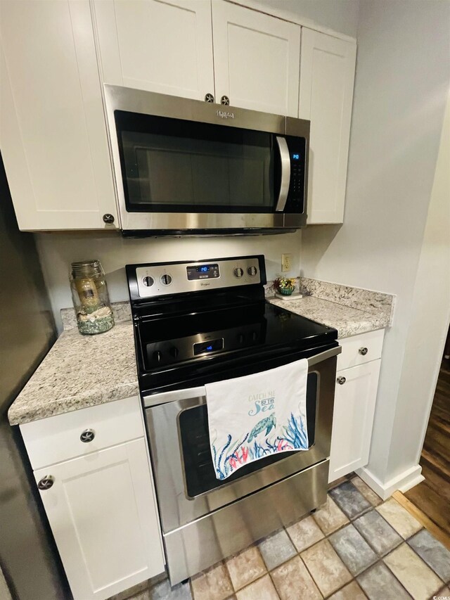 kitchen featuring stainless steel appliances, white cabinets, and light stone countertops