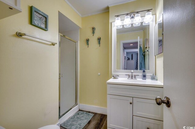 bathroom featuring a shower with shower door, vanity, wood-type flooring, and crown molding