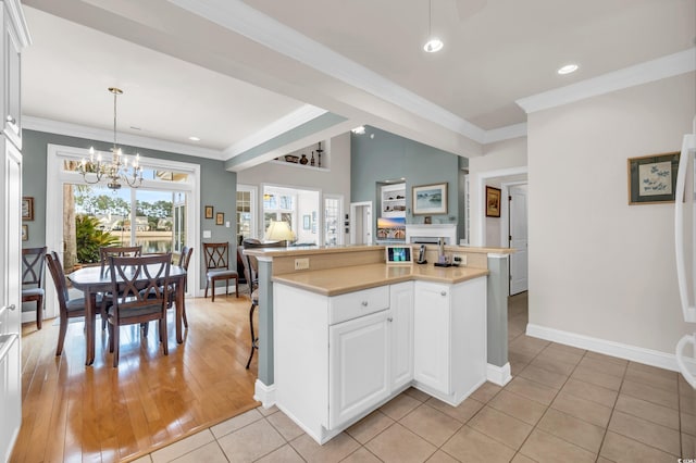 kitchen with pendant lighting, light tile patterned floors, a kitchen island, crown molding, and white cabinets