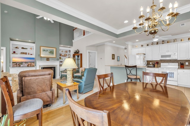 dining area featuring ornamental molding, light wood-type flooring, an inviting chandelier, and built in features