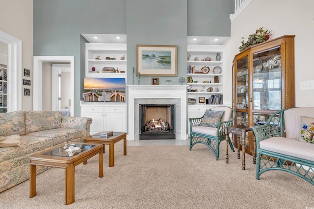 living room featuring a towering ceiling, built in shelves, and light colored carpet