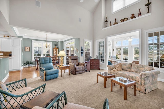 living room featuring a high ceiling, crown molding, light carpet, and ceiling fan with notable chandelier