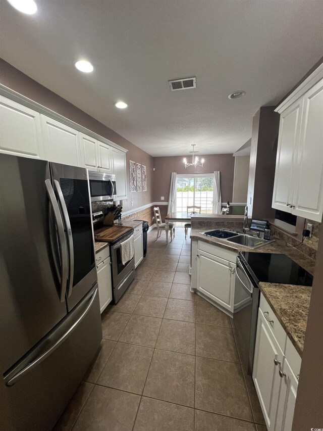 kitchen featuring stainless steel appliances, white cabinets, an inviting chandelier, decorative light fixtures, and light tile patterned flooring