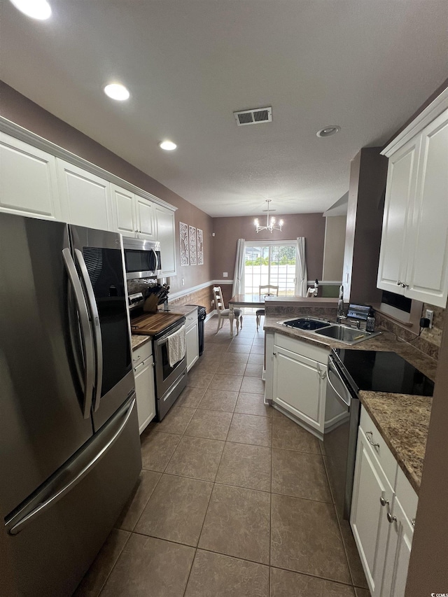389 Cabo Loop, Myrtle Beach, SC 29588 - kitchen with stainless steel appliances, white cabinets, a chandelier, dark tile patterned floors, and recessed lighting