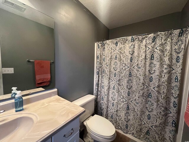 bathroom with toilet, a textured ceiling, and vanity