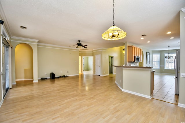 kitchen featuring white refrigerator, decorative light fixtures, light wood-type flooring, ceiling fan with notable chandelier, and crown molding