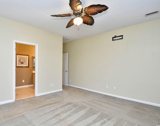 unfurnished room with ceiling fan, light colored carpet, and a textured ceiling