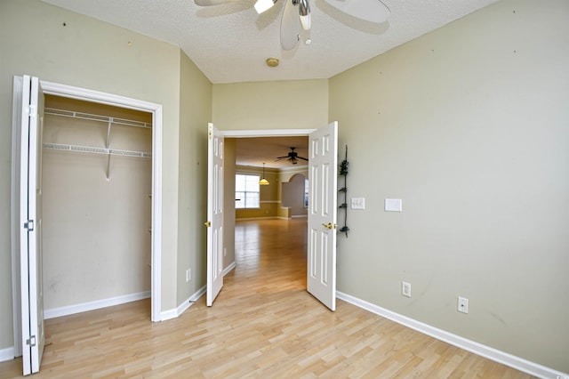 unfurnished bedroom with ceiling fan, light wood-type flooring, a closet, and a textured ceiling