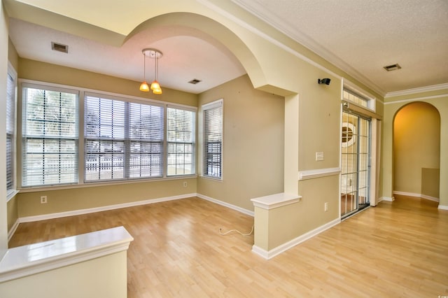 spare room with a textured ceiling, ornamental molding, and light hardwood / wood-style flooring