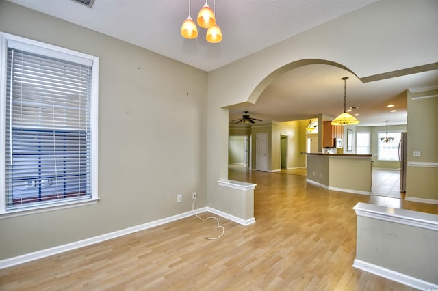 spare room featuring ceiling fan with notable chandelier and light hardwood / wood-style flooring