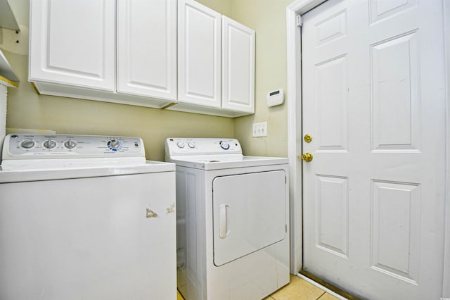 laundry room featuring washer and dryer, light tile patterned floors, and cabinets