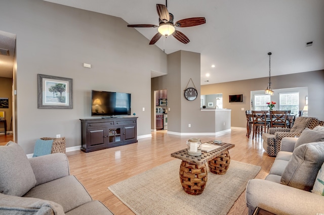 living room featuring high vaulted ceiling, ceiling fan, and light wood-type flooring