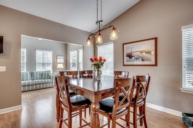 dining space featuring light wood-type flooring and vaulted ceiling