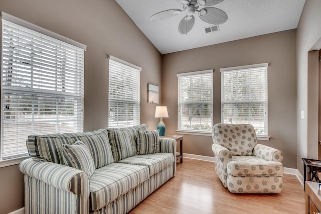 living room with ceiling fan, a healthy amount of sunlight, vaulted ceiling, and light hardwood / wood-style flooring