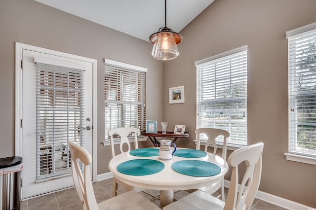 dining space with vaulted ceiling and light tile patterned flooring