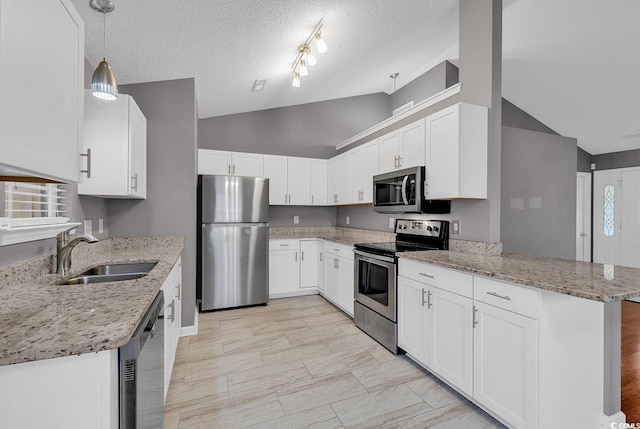 kitchen featuring stainless steel appliances, hanging light fixtures, light stone countertops, sink, and white cabinetry