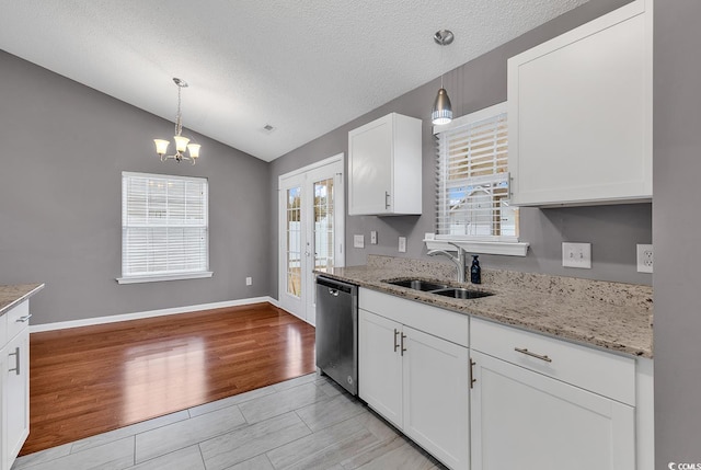 kitchen featuring stainless steel dishwasher, vaulted ceiling, pendant lighting, and white cabinetry