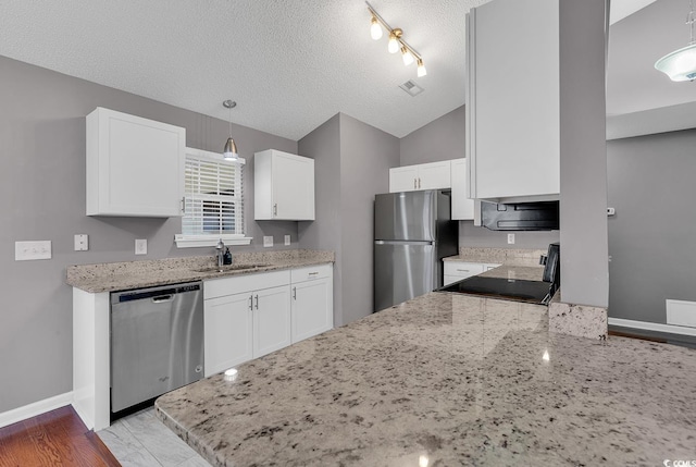 kitchen with stainless steel appliances, white cabinetry, sink, and hanging light fixtures