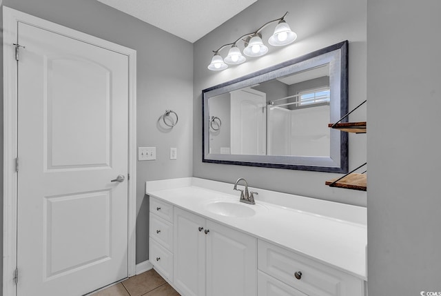 bathroom with tile patterned flooring, a shower, a textured ceiling, and vanity