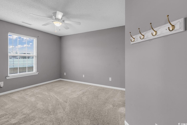 carpeted spare room featuring a textured ceiling and ceiling fan