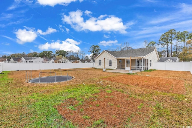 back of property with a patio area, a trampoline, and a yard