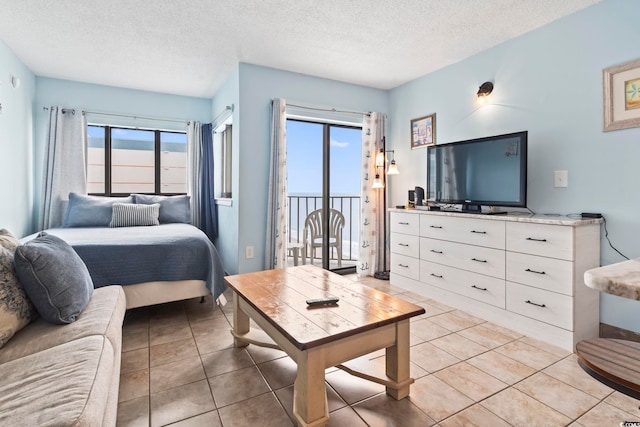 tiled bedroom with a textured ceiling, access to outside, and multiple windows