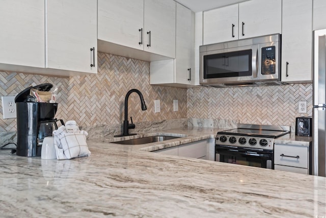 kitchen with appliances with stainless steel finishes, white cabinets, and sink