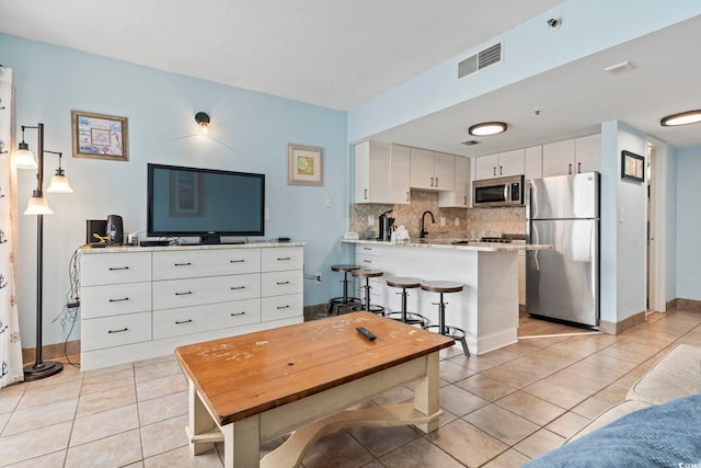 kitchen featuring kitchen peninsula, stainless steel appliances, decorative backsplash, pendant lighting, and white cabinets