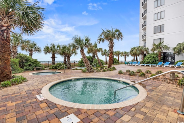 view of pool with a hot tub and a patio