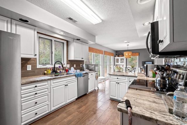 kitchen with white cabinetry, range, tasteful backsplash, pendant lighting, and stainless steel dishwasher