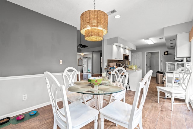 dining area with ceiling fan with notable chandelier and hardwood / wood-style flooring