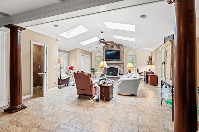 living room featuring ornate columns, a fireplace, ornamental molding, ceiling fan, and lofted ceiling with skylight