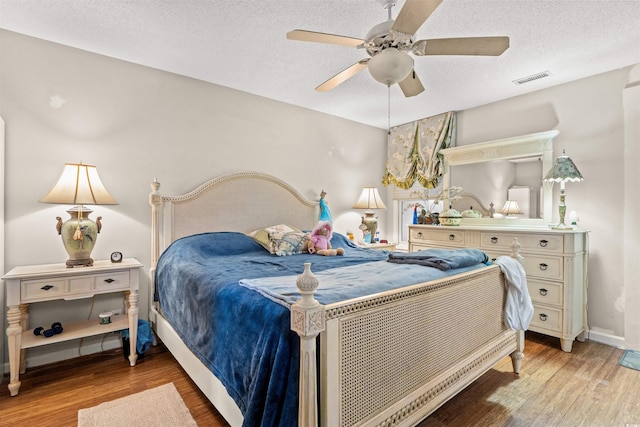 bedroom with ceiling fan, light wood-type flooring, and a textured ceiling