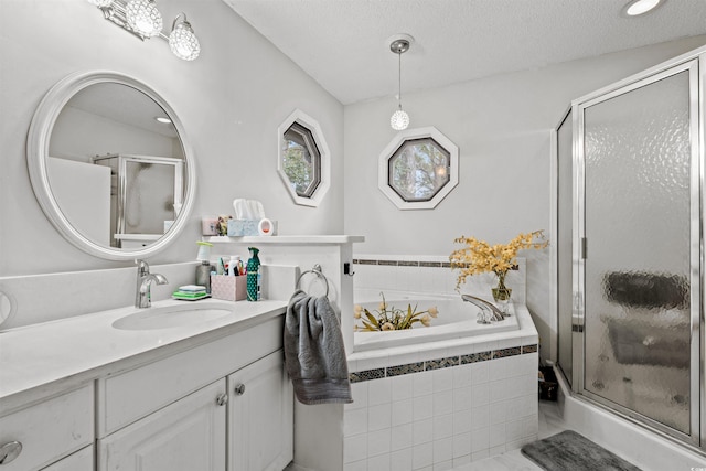 bathroom featuring a textured ceiling, shower with separate bathtub, and vanity